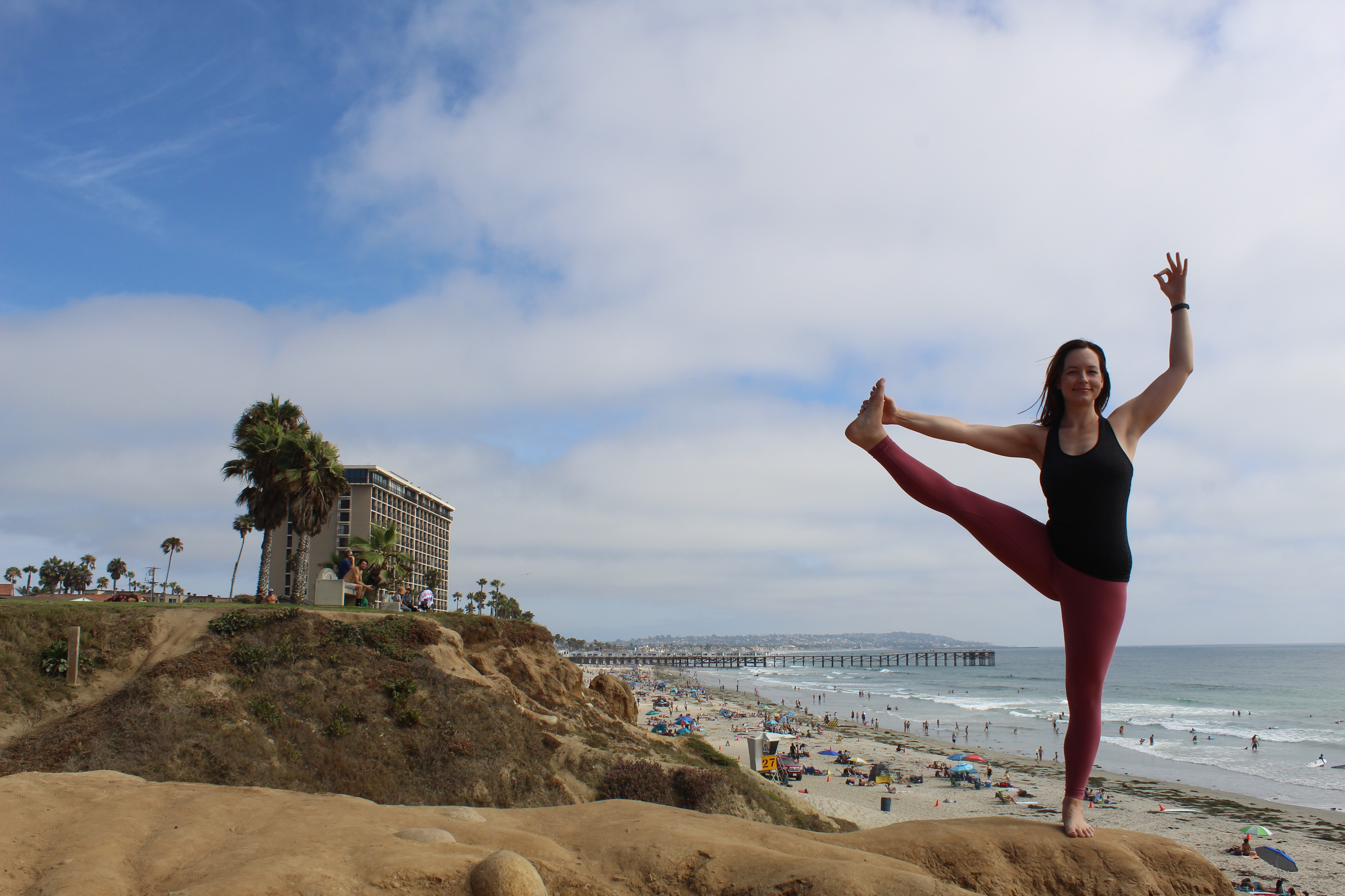 yogi posing on a beach side cliff