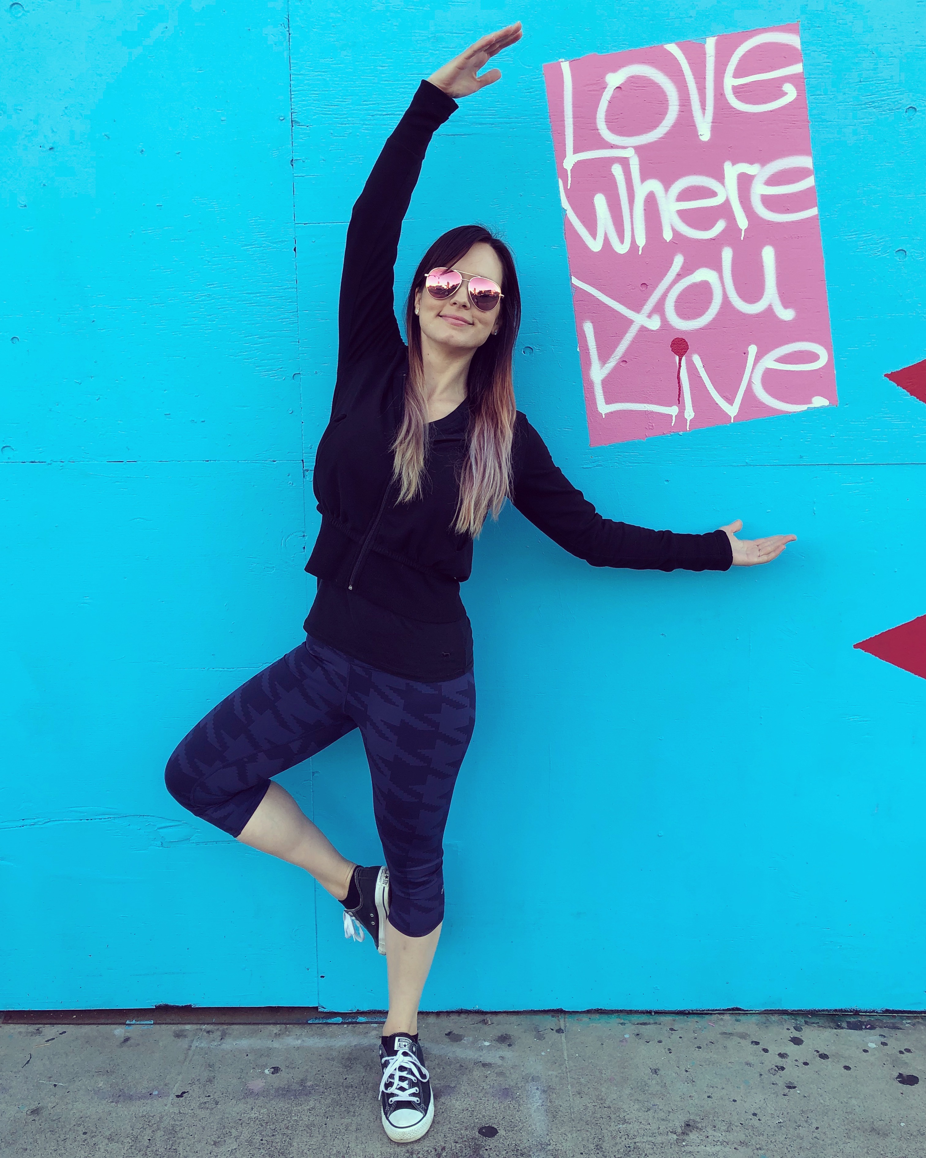 yogi posing while framing street art saying 'love where you live'