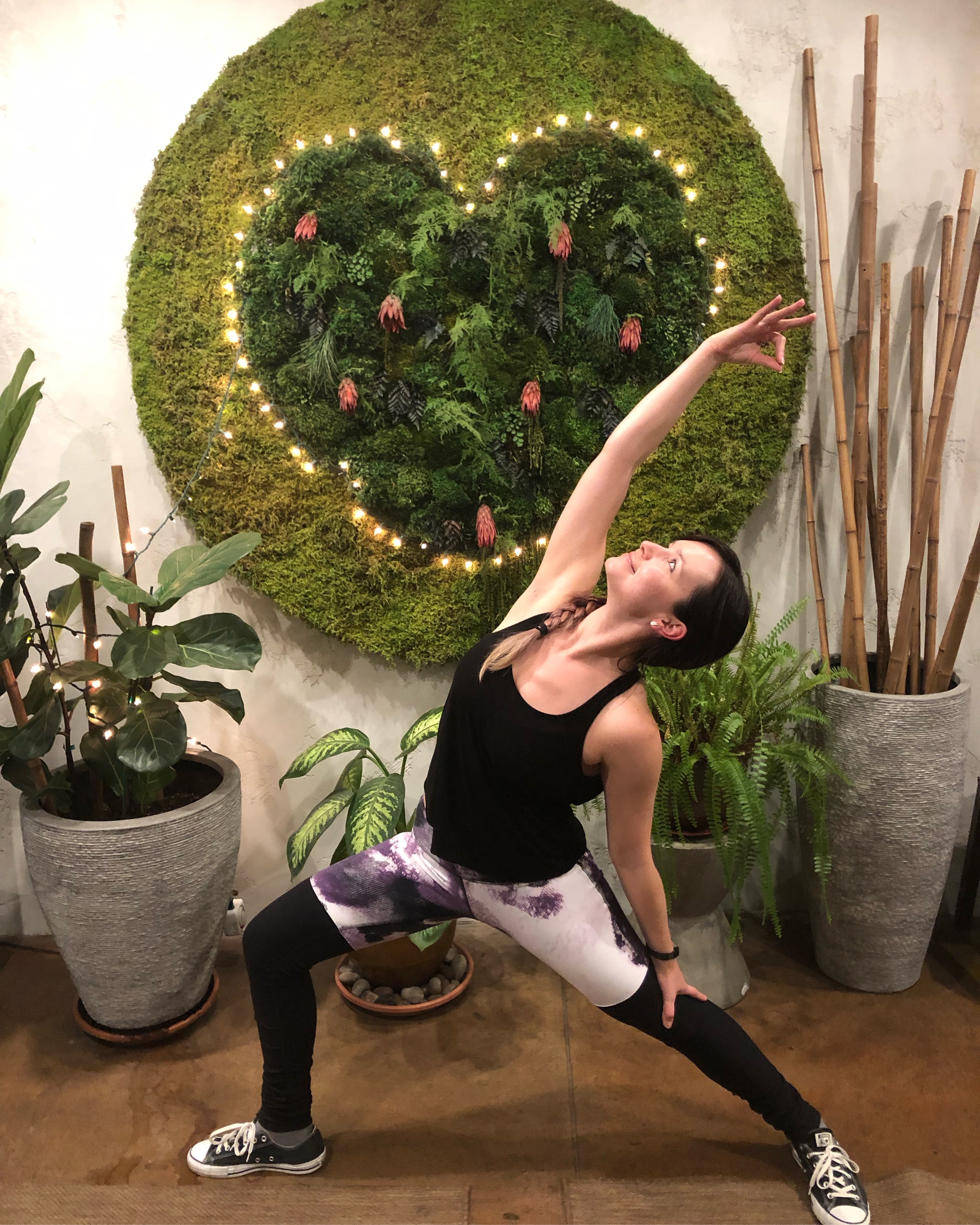 yogi posing in front of heart shaped plant wall decoration