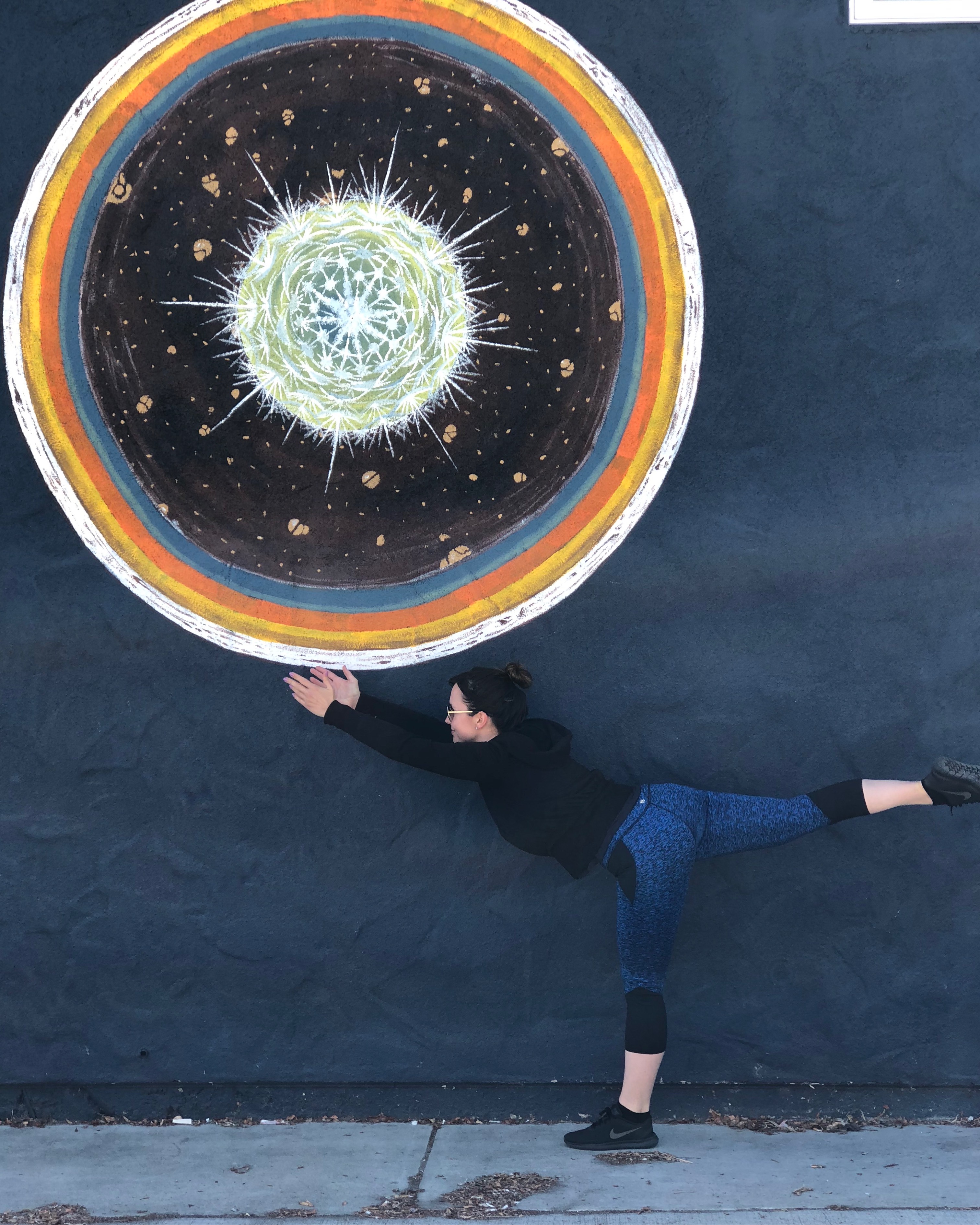 yogi posing as if holding a giant sun painting